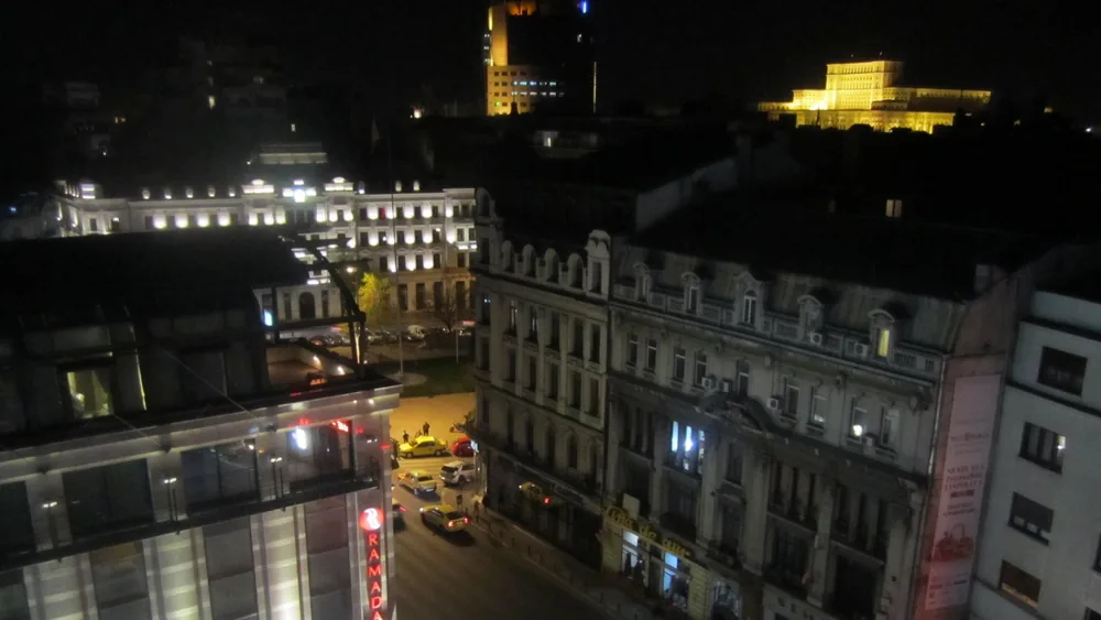 Bucureștiul noaptea, văzut de sus din Piața Universității, cu Palatul Parlamentului luminat în depărtare